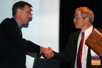 Photo of Gordon Sharp accepting the award and shaking hands with Dan Doyle
